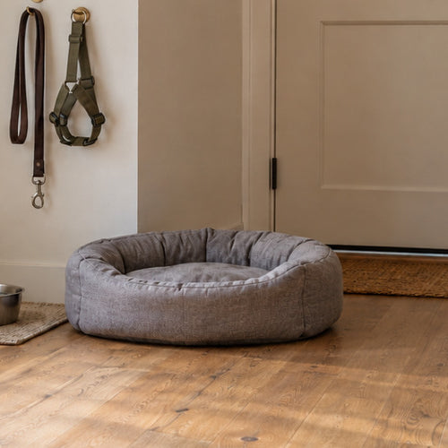 Living room with a gray dog bed, a steel water bowl, and a leash and harness on wall hooks beside a front door