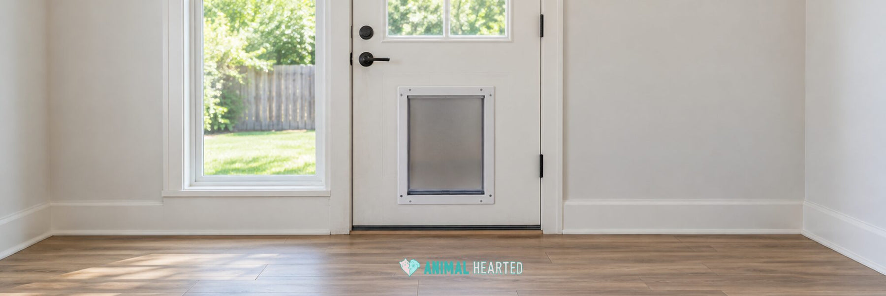 A white back door with a pet door set low in it, a window beside it showing a lawn, and an empty wood floor in front
