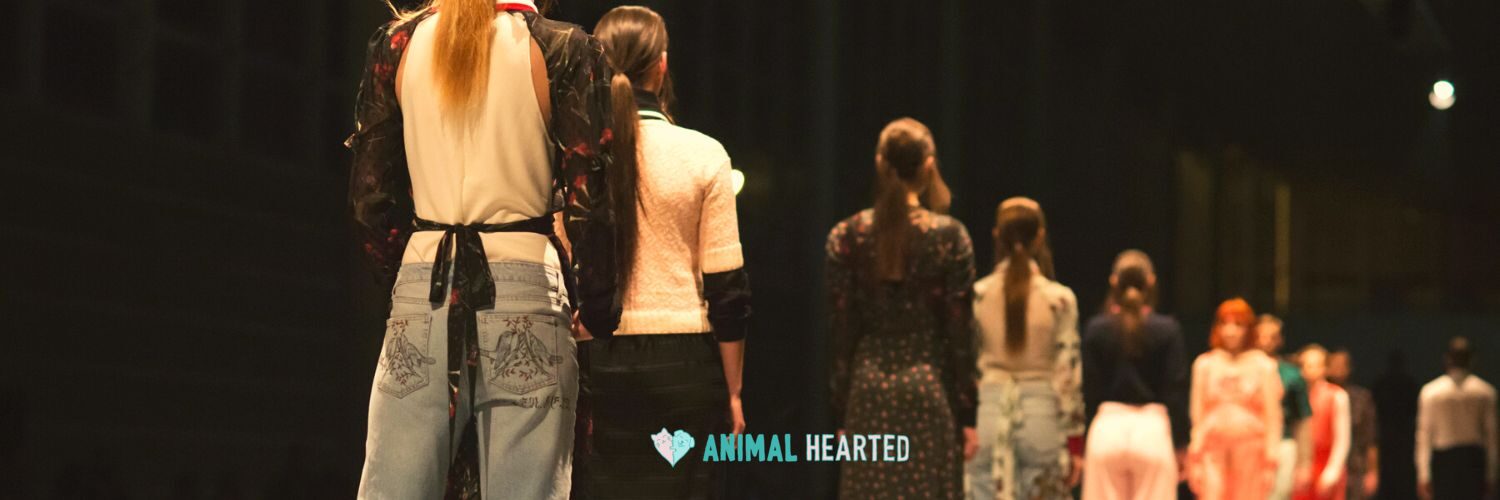 Models seen from behind walking in a line on a dark runway
